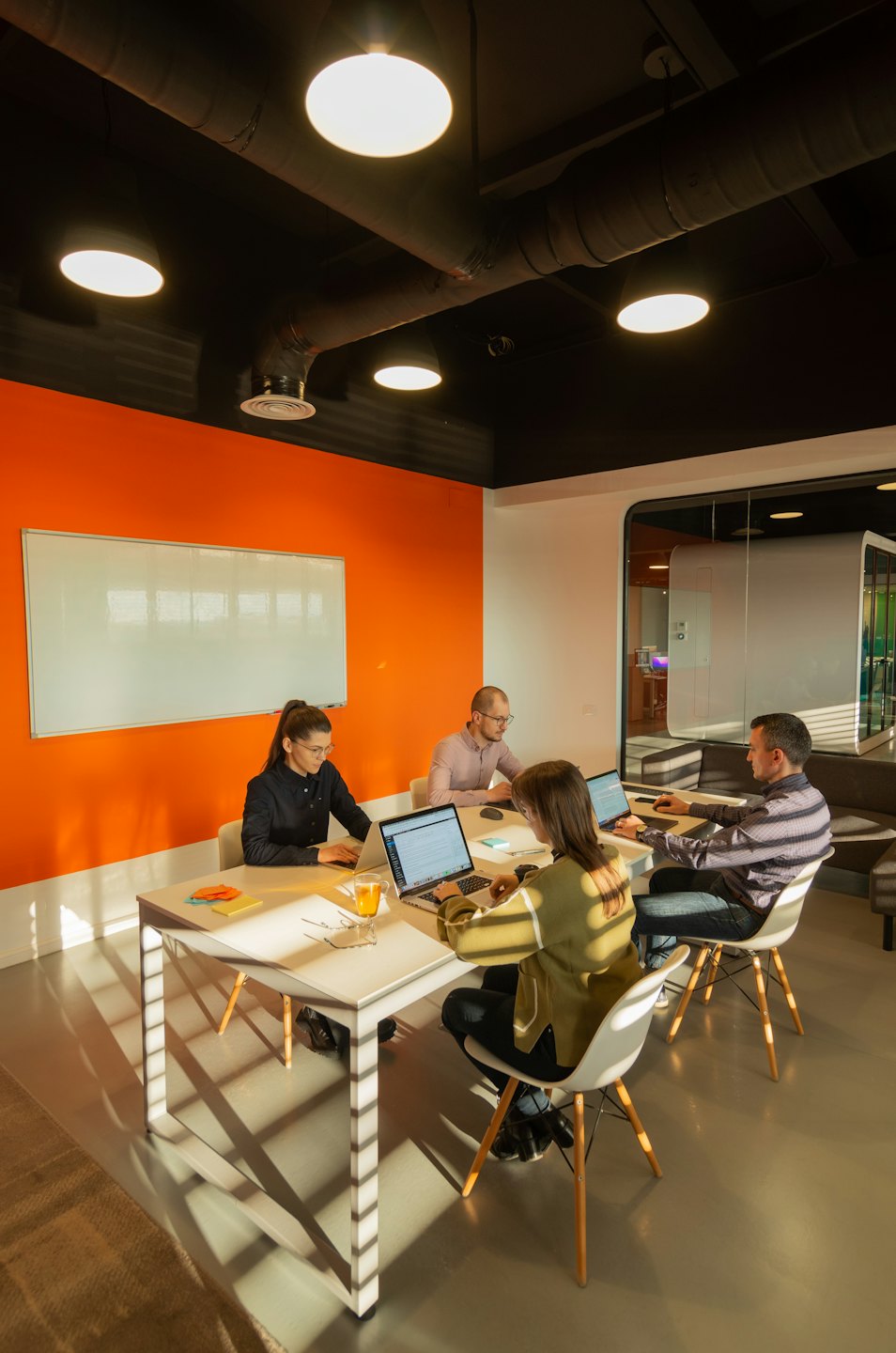 Professionals collaborate on laptops at a modern office table.